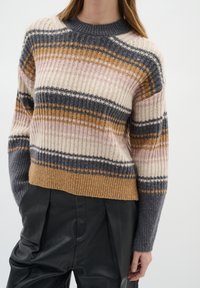 Gestreifter Pullover in Creme-, Pink-, Grau- und Brauntönen; gerippte Textur; runder Ausschnitt; kurzes Design; kombiniert mit schwarzen Lederhosen.