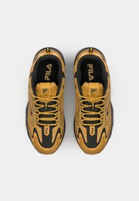 Black and mustard yellow sneakers with textured surfaces, wavy design, round toe, thick black sole, and Fila branding on the tongue.