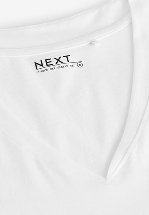 Tricou alb cu mâneci tip capac și decolteu în V, realizat din bumbac moale, având o textură netedă și cusături fine, cu o etichetă care indică marca și mărimea.