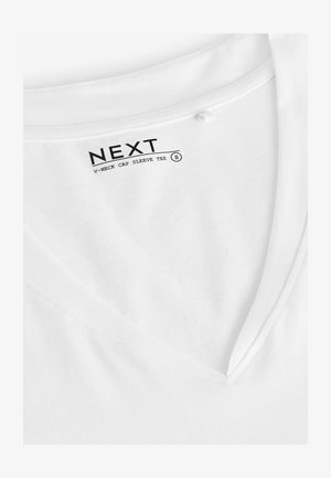 Vit T-shirt med kepsärmar och V-ringning, tillverkad av mjuk bomull, med en slät textur och ren sömnad, samt en etikett som anger märke och storlek.