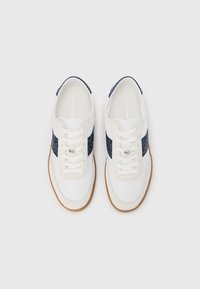 Bijele platnene tenisice s mornarskim uzorkom na bočnoj strani, okruglim vrhom i ravnim gumenim potplatom. Imaju vezice za vezanje i logo na ulošku.