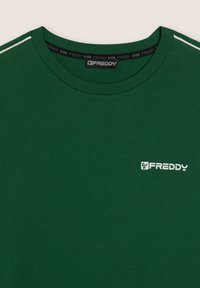 T-shirt verde in morbido tessuto, con collo rotondo, maniche corte e strisce bianche sui lati. Logo "FREDDY" in bianco sul davanti.