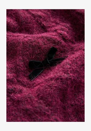 Material texturat mauve cu un aspect moale și pufos; prezintă un accesoriu sub formă de fundă neagră din catifea integrat în material.