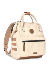 Beiger Canvas-Rucksack mit braunen Lederakzenten, doppelten Tragegriffen oben, verstellbaren Trägern, vorderer Reißverschlusstasche und runder Logo-Patch.