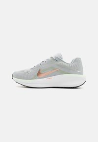 Baskets de course Nike gris clair avec un swoosh rose gold, semelle intermédiaire blanche avec amorti à air, et semelle extérieure noire, vues de côté.