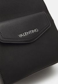 Black leather bag featuring a flap closure with a silver VALENTINO logo. Smooth texture with subtle stitching detail.