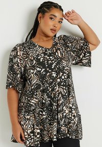 Top bianco e nero con motivi di farfalle, maniche corte a sbuffo e scollatura a V, realizzato in un tessuto leggero. Design fluido, vestibilità ampia.