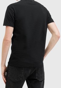 T-shirt di cotone nero con un design semplice, maniche corte e collo girocollo classico. Il tessuto appare morbido e leggermente strutturato.