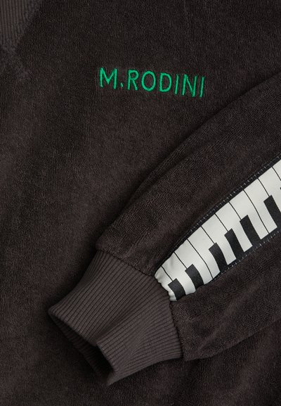 Felpa marrone scuro con ricamo verde "M.RODINI". Presenta un tessuto testurizzato e un polsino a costine con un accento a stampa tasti di pianoforte sulla manica.