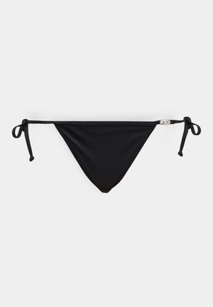 Parte inferior de bikini negro con lazos laterales y un pequeño broche plateado en el lado derecho, mostrado sobre un fondo liso y claro.