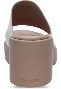 Scivolo bianco in schiuma con un tacco platform spesso di colore beige. Esterno liscio, schienale aperto, soletta testurizzata con motivi circolari. Logo "Crocs" sul tacco.
