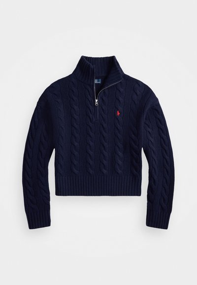 Temno modra pulover z žičnim pletenjem in visokim rebrastim ovratnikom ter pol zadrgo. Ima majhen rdeč logotip na prsih in rebraste manšete.