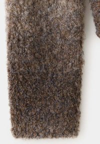 Gros plan sur un tissu tricoté en laine marron texturé avec une surface duveteuse et bouclée montrant des fibres détaillées et le motif de couture.