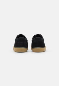 Zapatillas negras de ante con suela de goma, con un diseño de corte bajo y cuello acolchado, marcado mínimo, y detalles de costura.