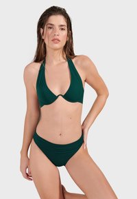 Zielony bikini na halter z głębokim dekoltem i gładką fakturą. Dół ma szeroką talię i umiarkowane krycie.