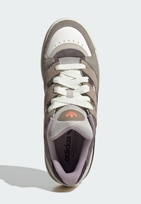 Višebojne tenisice koje kombiniraju smeđi nubuk i svijetlosivu mrežu. Imaju bijeli gumeni đon i istaknute logotipne akcentne.