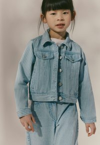 Lichtblauwe gestreepte denimjacket met zilveren knopen, borstzakken en een cropped ontwerp, gecombineerd met een bijpassende broek in een vergelijkbaar patroon.