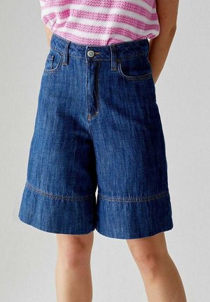 Shorts in denim blu con vestibilità ampia, orlo risvoltato, due tasche frontali e chiusura a bottone con una patta decorativa.