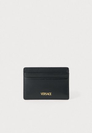 Fekete bőrből készült kártyatartó, több rekesszel és az előlapján dombornyomott arany "VERSACE" logóval. Sima textúra és egyszerű, elegáns kialakítás.