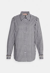 Chemise à carreaux vichy noir et blanc à boutons, avec col pointu, manches longues et boutons décoratifs aux poignets.