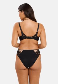 Ensemble de lingerie noire comprenant un soutien-gorge avec des accents en dentelle et des bretelles réglables, ainsi que des culottes taille haute avec des panneaux latéraux en dentelle.