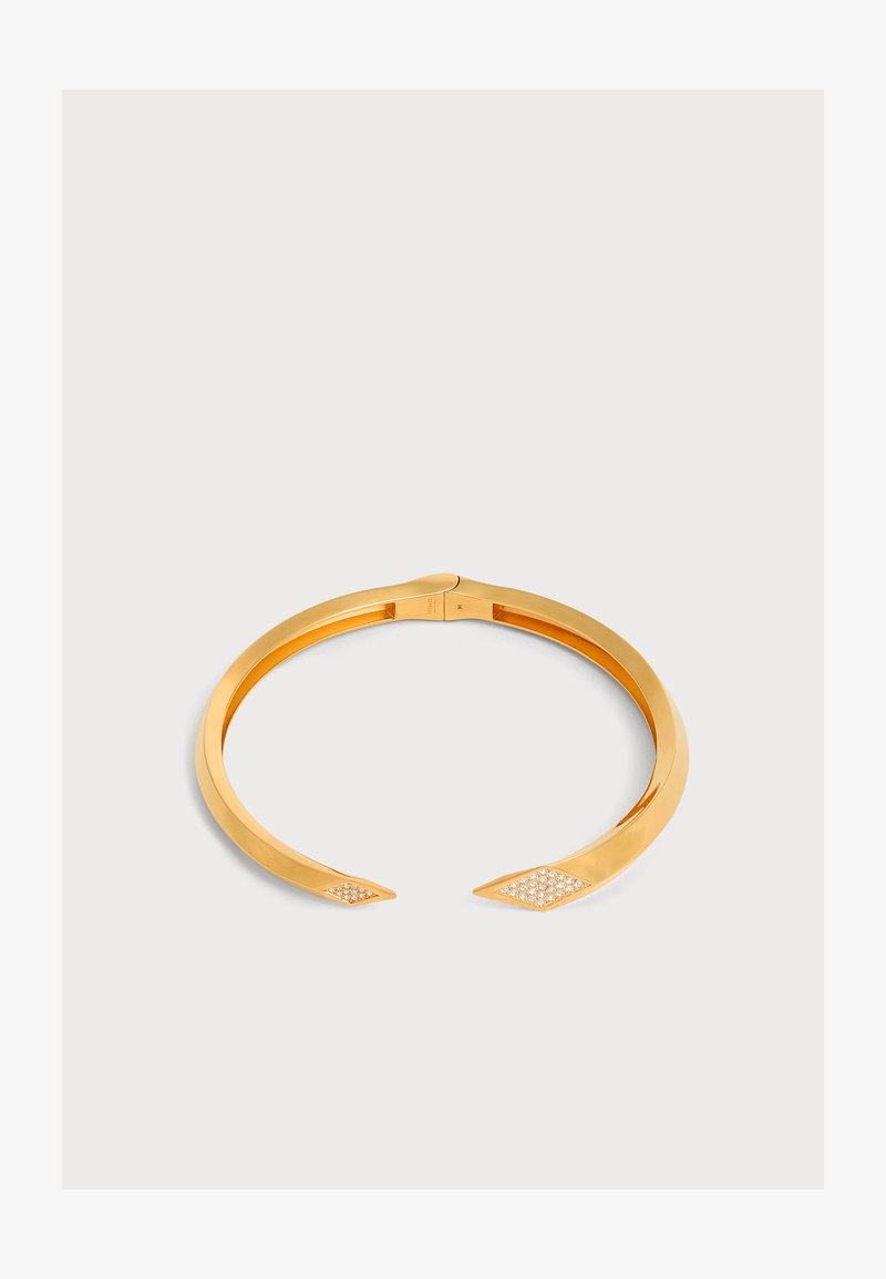 Bracelet manchette ouvert en or avec des extrémités pointues, chacune décorée de petites pierres blanches, sur un fond clair uni.
