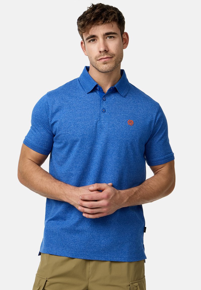 Polo bleu avec un tissu texturé, manches courtes et un col traditionnel. Présente un petit logo orange sur la poitrine.