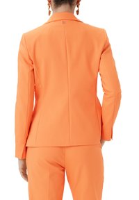 Orange maßgeschneiderte Blazer mit strukturierten Schultern, einzelner Rückenschlitz und tailliertem Schnitt. Glatter Stoff mit subtiler glänzender Oberfläche.