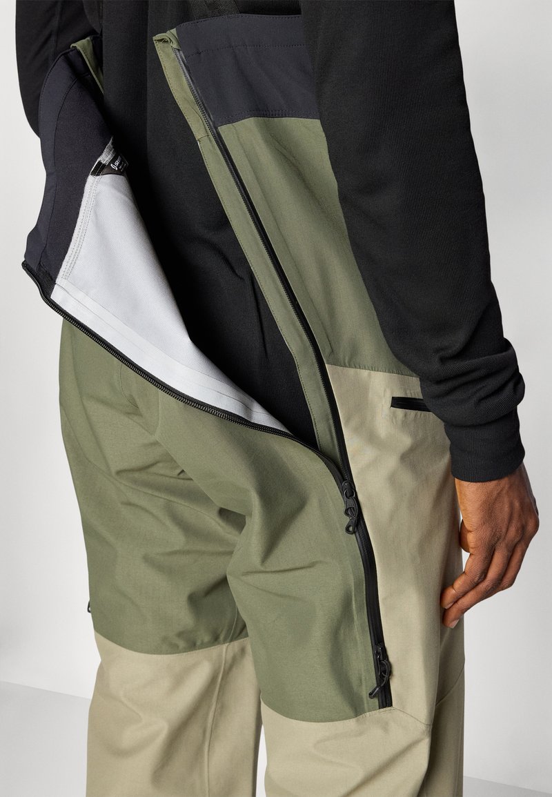 Spodnie cargo w dwóch kolorach, oliwkowym i beżowym. Posiadają zamykane na zamek boczne kieszenie, gładką teksturę materiału oraz unikalny krój.