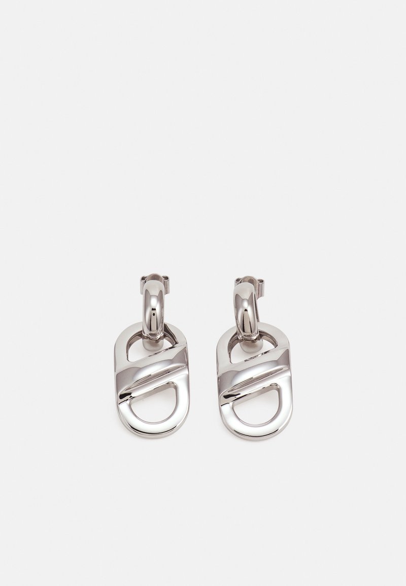 Paire de boucles d'oreilles pendantes en métal argenté brillant avec des formes géométriques abstraites et fermoirs à charnière en forme de créole sur fond blanc.
