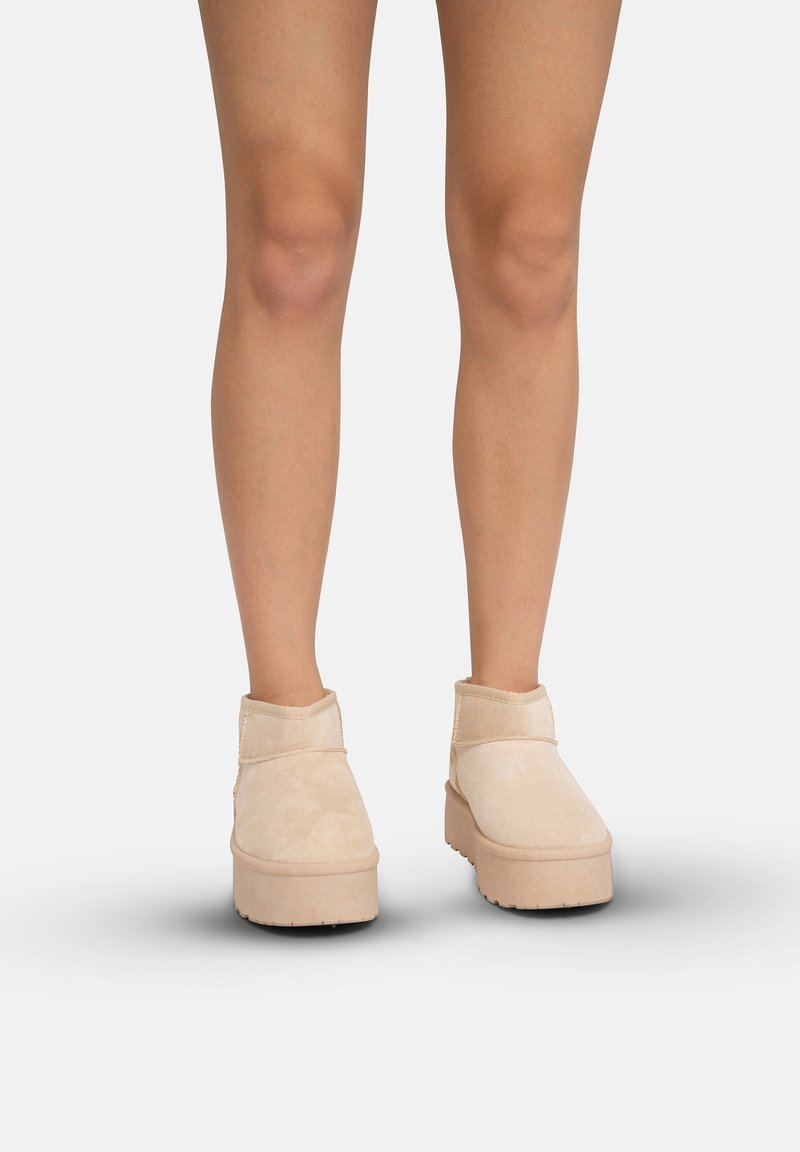 Botines de ante beige con un cuello redondeado bajo y una suela de plataforma gruesa. Presenta un sutil detalle de costura y una superficie texturizada.