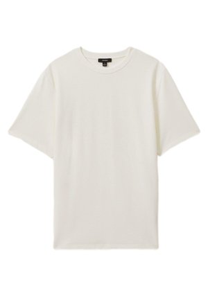 Enkel hvid T-shirt med korte ærmer og rund hals med tekstureret stof og et sort mærke inde i halskanten.