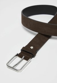 Cintura in suede marrone con interno nero, caratterizzata da una fibbia rettangolare in argento e un dettaglio con rivetto vicino alla fibbia. Texture liscia.