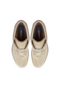 Zapatos de tobillo de ante beige con punta redonda, cordones a tono y collar acolchado. La etiqueta interior presenta un diseño de estrellas azules y blancas.