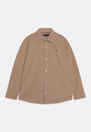 Camisa beige de manga larga con botones, cuello y pequeño logo bordado en el pecho izquierdo.