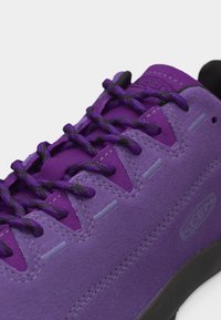 Μοβ σουέντ αθλητικό παπούτσι με σκουρόμωβ κορδόνια, μαύρη σόλα και ορατή ραφή.