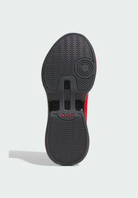 Black rubber shoe sole with herringbone pattern, featuring red accents and three small red dots near the center. Circular detail on the right.