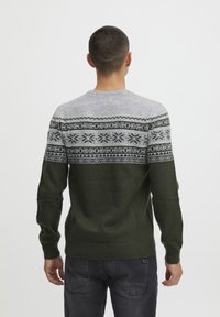 Strikket sweater med en grøn krop og en grå mønstret bærestykke med snefnugs- og geometriske designs. Ribbet manchetter og kant.