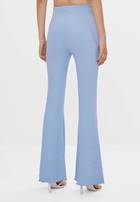 Ljusblå ribbat stickade utsvängda byxor med hög midja och råkant. Tillsammans med ljusa klackar.