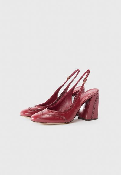 Red leather slingback heels featuring a rounded toe, perforated accents, and a chunky block heel. Smooth texture with a polished finish.