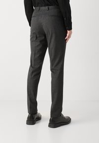 Grijze op maat gemaakte broek met een gestructureerde afwerking, voorzien van een vlakke voorkant, riemlussen en achterzakken, gecombineerd met zwarte nette schoenen.