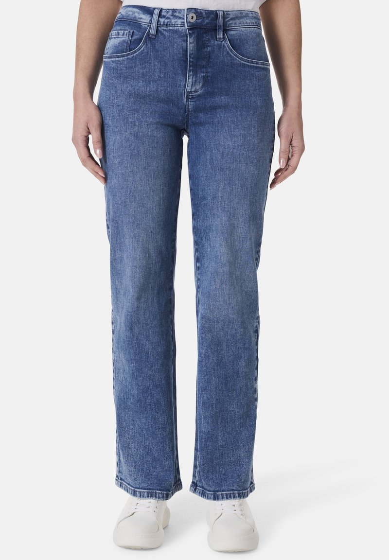 Blaue Denim-Jeans mit geradem Bein, ausgestattet mit Fronttaschen, einem Knopfverschluss und dezenten Ausbleichungen. Kombiniert mit weißen Sneakern.