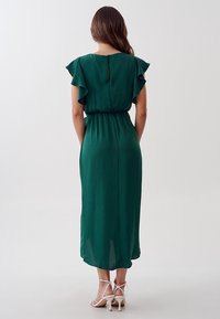 Abito midi verde con maniche ruffle corte, vita elastica e schiena con apertura a chiave. Realizzato in tessuto leggero, con una texture liscia.