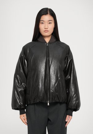 Giacca bomber nera con finitura lucida, colletto a coste e vita elastica. Presenta una chiusura con zip e maniche ampie e morbide.