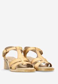 Sandalias de cuero beige con tacón bloque, que cuentan con múltiples correas y cierre de hebilla. Forro interior suave y detalles cosidos.
