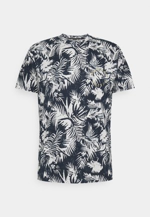 Camiseta azul marino de manga corta con estampado blanco de hojas y flores tropicales y pequeño texto amarillo en la parte superior del pecho.
