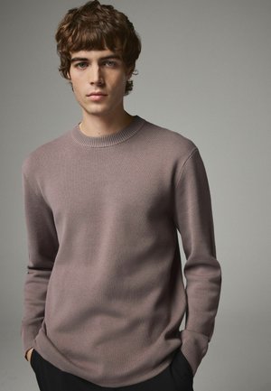Pull en tricot doux lavande avec un col rond côtelé et des manches longues, présentant une texture lisse et un design minimaliste.