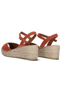 Rode suède wedge sandalen met een gevlochten jute platform, voorzien van kruisbanden en een gespsluiting voor een veilige pasvorm.