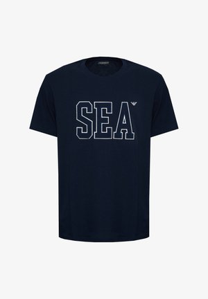 T-shirt blu navy a maniche corte con grandi lettere a blocchi bianche contornate "SEA" e un piccolo logo di un'aquila sopra la "A" sul petto.