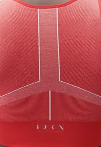 Roter Sport-BH mit strukturiertem Stoff, der horizontale und vertikale Muster aufweist, weißen Nähdetails und einem Logo am unteren Rand.